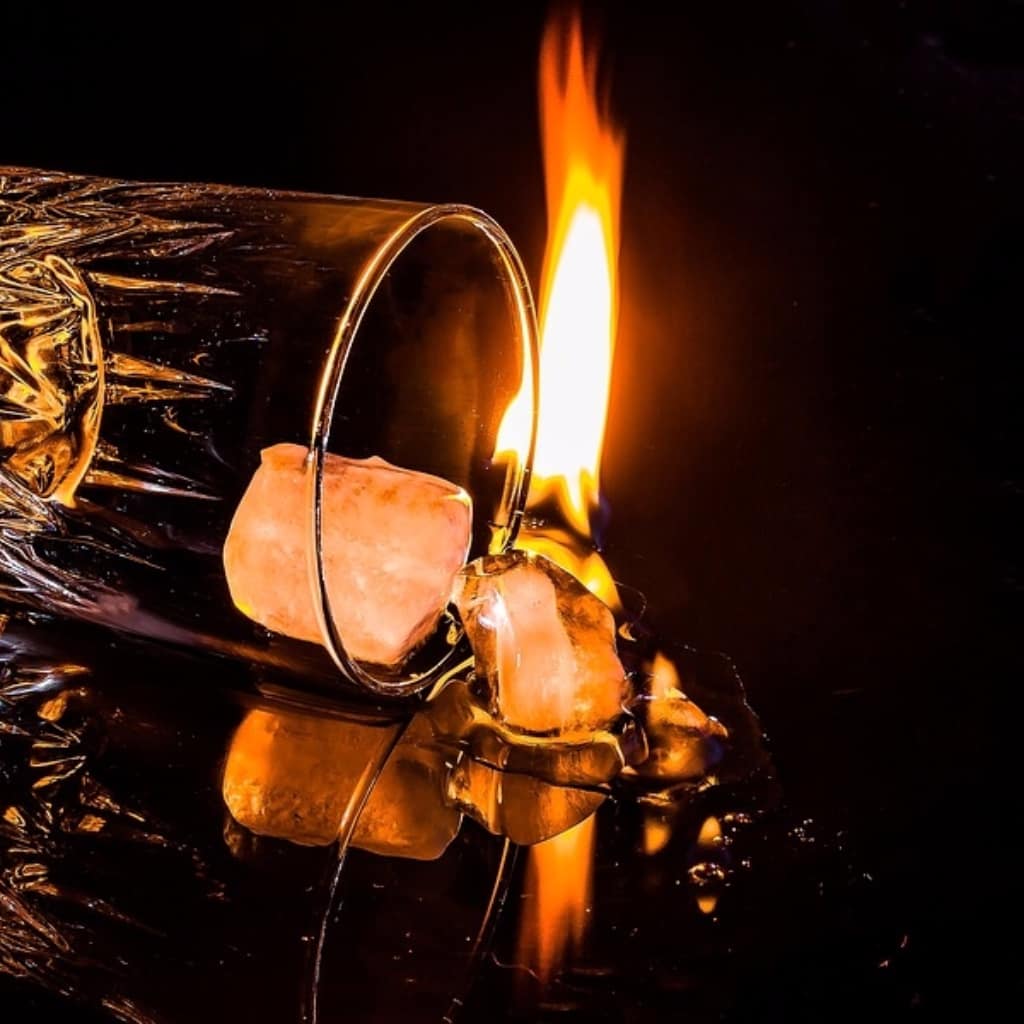 figura de copo emborcado saindo pedras de gelo e uma chama ao fundo