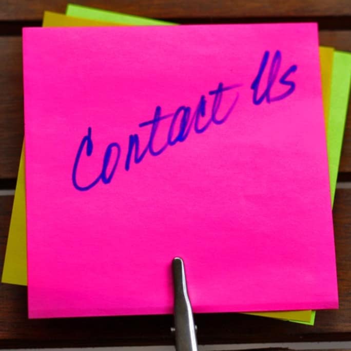 visão de cima de um papel lembrete rosa com a inscrição em azul contact us