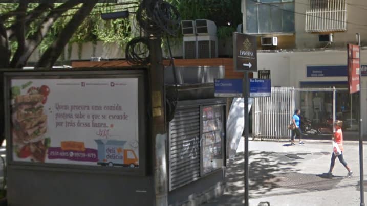 foto do outdoor da loja delidelicia afixado na parede oposta a da entrada da banca de jornal que fica em frente ao estabelecimento